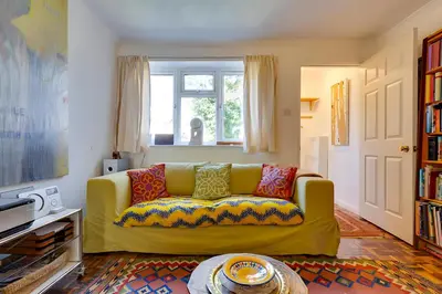 a yellow couch with colorful pillows in a living room at Pass the Keys Charming Ground Floor Flat with Free Parking in Cambridge