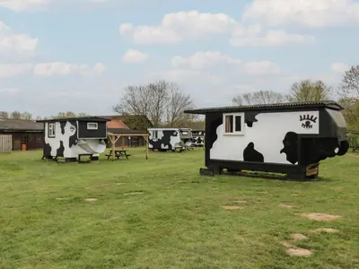 a couple of trailers in a grass field at Buttercup Cow Shed 3 in Woodbridge