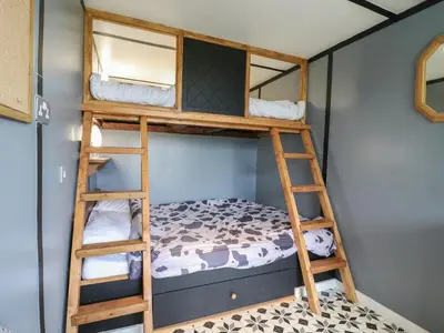 a bunk bed room with two bunk beds and a ladder at Dozy Dotty Cow Shed 4 in Woodbridge
