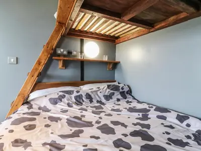 a bed in a bedroom with a wooden roof at Dozy Dotty Cow Shed 4 in Woodbridge