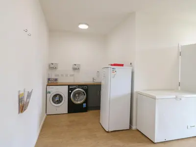 a laundry room with a refrigerator and a washing machine at Daisy Cow Shed 1 in Woodbridge