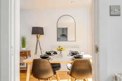 a dining room with a table with chairs and a mirror at Modern Spacious 4 Bedroom 3 Bathroom House by Trinity Stays Short Term Lets & Serviced Accommodation Cambridge in Cambridge