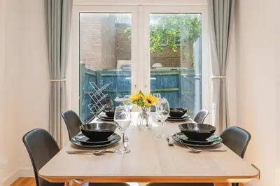 a dining room table with chairs and a table with glasses at Modern Spacious 4 Bedroom 3 Bathroom House by Trinity Stays Short Term Lets & Serviced Accommodation Cambridge in Cambridge