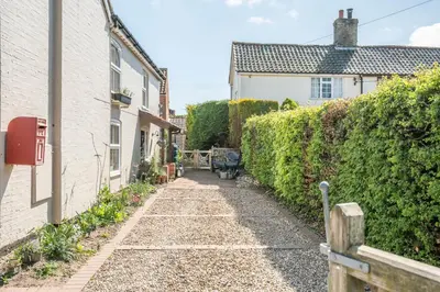 a narrow alley between two buildings with a hedge at Stable Cottage, Friston in Friston
