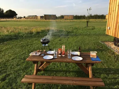 a bird standing on a picnic table in a field at Shepherds Hut 7 in Bedfield