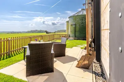 a patio with a table and chairs and a fence at Gin and Toffee Carriage in Thaxted