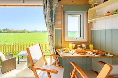 a kitchen with a table and chairs and a window at Gin and Toffee Carriage in Thaxted