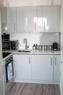 a kitchen with white cabinets and a sink and a microwave at Promenade Apartment in Maldon