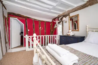 a bedroom with a bed and a red wall at Hylton Cottage, Lavenham in Lavenham