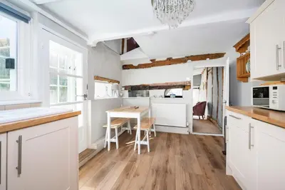 a kitchen with white cabinets and a table and chairs at Hylton Cottage, Lavenham in Lavenham