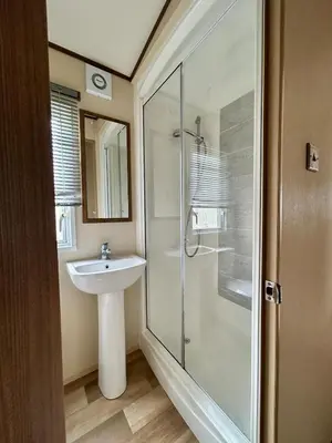 a bathroom with a sink and a glass shower at VerbLake 5 Berth Caravan St Osyth Beach Holiday Park in Saint Osyth