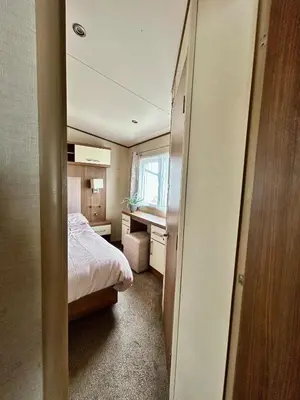 a small bedroom with a bed and a desk at VerbLake 5 Berth Caravan St Osyth Beach Holiday Park in Saint Osyth