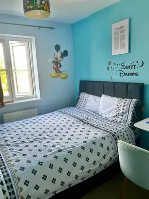 a bedroom with a bed with a mickey mouse sign on the wall at Rooms in Granary House, Newmarket in Newmarket