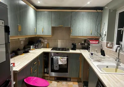 a kitchen with wooden cabinets and a pink stool at Rooms in Granary House, Newmarket in Newmarket