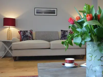 a living room with a couch and a vase of flowers at Sea Crest in Aldeburgh