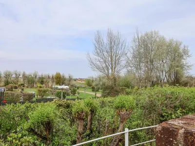 a garden with trees and bushes and a fence at Sea Crest in Aldeburgh