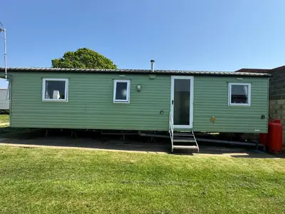 a green house with a ladder in a yard at Cabana Escape in Little Clacton