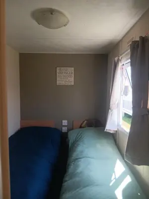 a small bedroom with a bed and a window at Cabana Escape in Little Clacton
