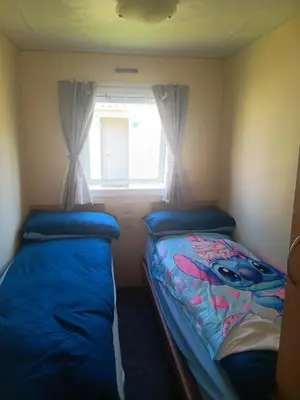 two beds in a small room with a window at Cabana Escape in Little Clacton