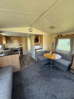 a living room with a table and a kitchen at Cabana Escape in Little Clacton