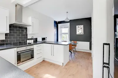 a kitchen with white cabinets and a black wall at Cosy 3 bedroom house with Free parking and WiFi in Colchester
