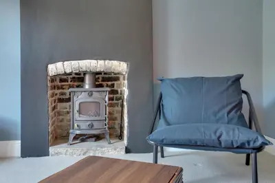 a blue chair in a living room with a fireplace at Cosy 3 bedroom house with Free parking and WiFi in Colchester