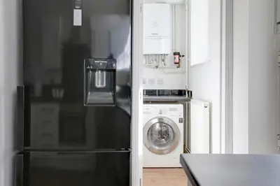 a kitchen with a refrigerator and a washing machine at Cosy 3 bedroom house with Free parking and WiFi in Colchester