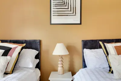 two beds in a bedroom with a lamp and a picture on the wall at Cosy 3 bedroom house with Free parking and WiFi in Colchester