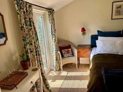 a bedroom with a bed and a window with a chair at Giffords Hall Garden Room in Shimpling