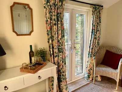 a room with a window and a table with a bottle of wine at Giffords Hall Garden Room in Shimpling