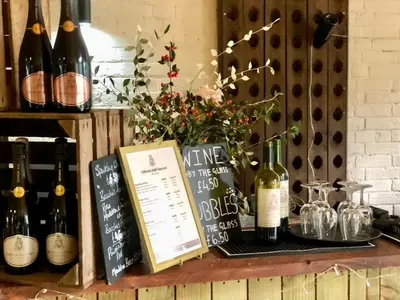 a table with bottles of wine and a menu at Giffords Hall Garden Room in Shimpling