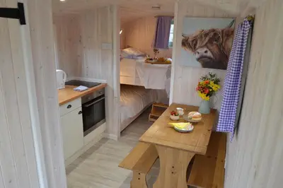 a small kitchen with a table in a tiny house at Shepherds Hut 6 in Bedfield