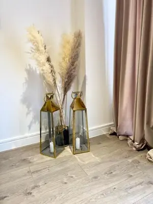 two gold lanterns and a vase with two candles at TT Maison in Brentwood