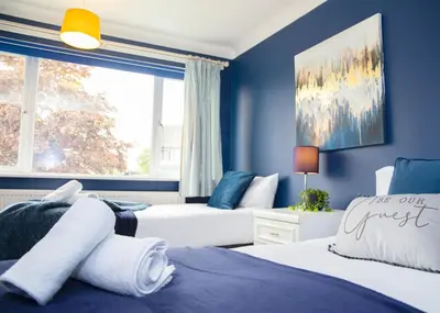two beds in a bedroom with blue walls and a window at Stylish and Spacious 3-Bed House Free Parking in Ipswich