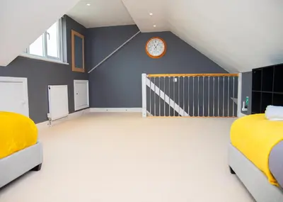 a bedroom with two beds and a clock on the wall at Stylish and Spacious 3-Bed House Free Parking in Ipswich
