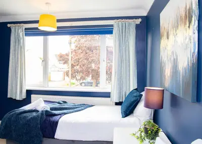a blue bedroom with a bed and a window at Stylish and Spacious 3-Bed House Free Parking in Ipswich