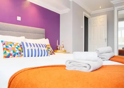 a bedroom with a bed with towels on it at Stylish and Spacious 3-Bed House Free Parking in Ipswich