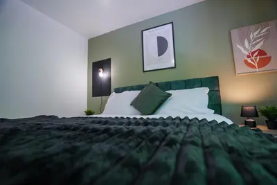a bedroom with a large bed with green walls at Spacious 5 Bedrooms Sleeps 9 3 Bath and Parking Ideal for Contractors in Chesfield