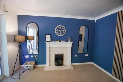 a blue room with a fireplace and a clock on the wall at Spacious 5 Bedrooms Sleeps 9 3 Bath and Parking Ideal for Contractors in Chesfield