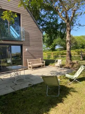 a patio with a table and chairs and a tree at Well Barn in Sudbourne