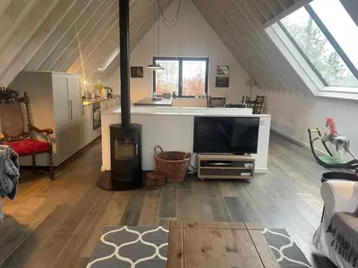 a living room with a flat screen tv in a attic at Well Barn in Sudbourne