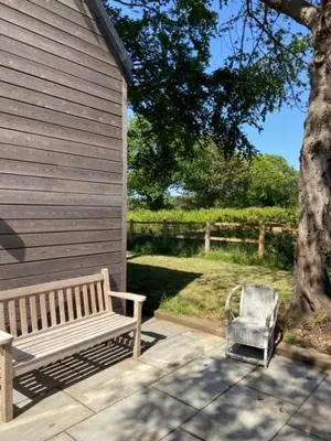 a bench sitting on a patio next to a tree at Well Barn in Sudbourne