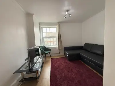 a living room with a black couch and a window at Lighthouse Lodge in Harwich
