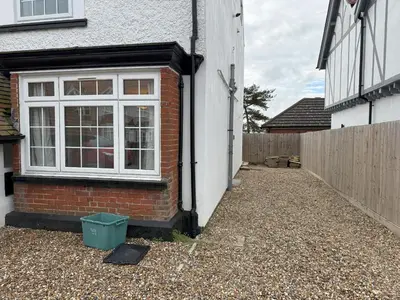 a brick house with a window and a fence at Lighthouse Lodge in Harwich