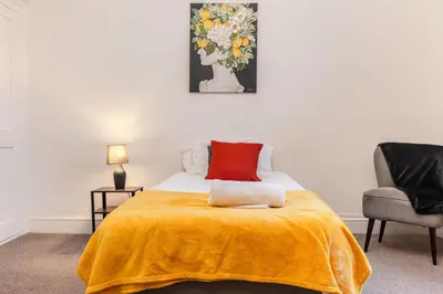 a bedroom with a bed with a yellow blanket and a chair at Modern bedrooms-Family -Free Parking-Hi-Speed WiFi-Sleeps 5 in Colchester