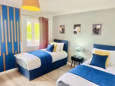 two beds in a bedroom with blue and white at Pleasant and Homely in Colchester