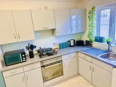 a kitchen with white cabinets and a stove top oven at Pleasant and Homely in Colchester