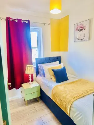 a bedroom with a bed and a table with a lamp at Pleasant and Homely in Colchester
