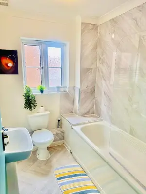 a bathroom with a tub and a toilet and a sink at Pleasant and Homely in Colchester