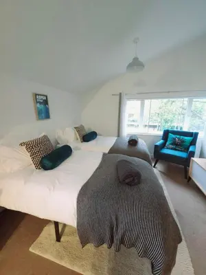 a bedroom with two beds and a blue chair at Canalside 1 bed flat in Hertford